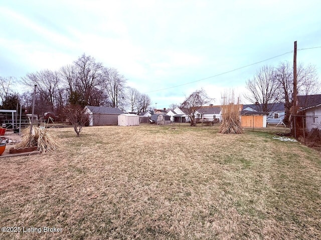 view of yard with a storage unit, an outdoor structure, fence, and a residential view