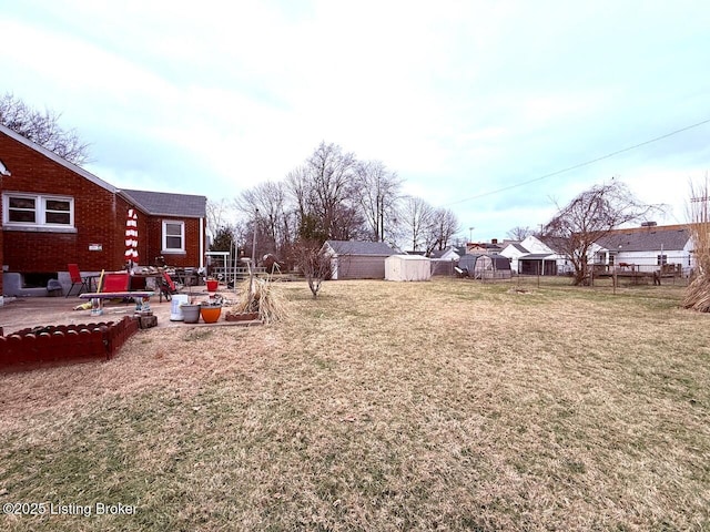 view of yard featuring a vegetable garden, a patio, a storage unit, fence, and an outdoor structure