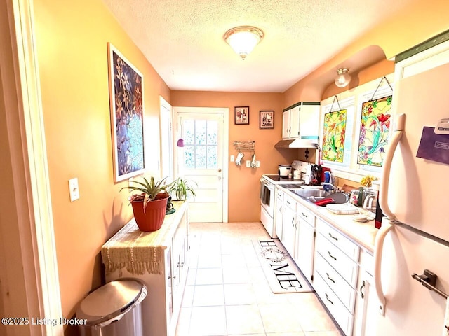 kitchen featuring light countertops, white appliances, white cabinets, and a textured ceiling