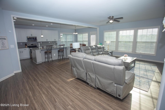 living room with dark wood-type flooring and ceiling fan