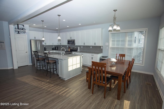 dining area with dark wood-type flooring, sink, and a notable chandelier