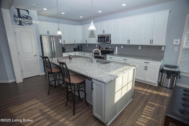 kitchen with stainless steel appliances, an island with sink, and white cabinets