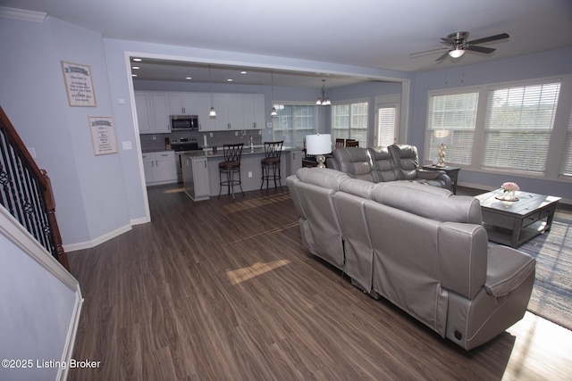 living room featuring ceiling fan, dark wood-type flooring, and a healthy amount of sunlight