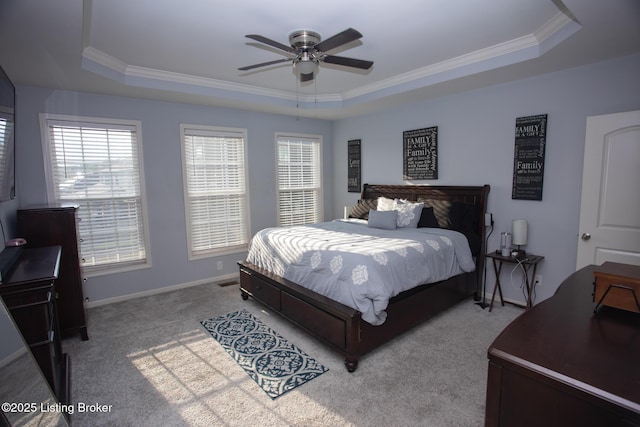 bedroom with a raised ceiling, crown molding, light colored carpet, and ceiling fan