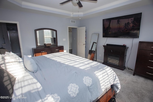 carpeted bedroom featuring crown molding, a tray ceiling, and ceiling fan