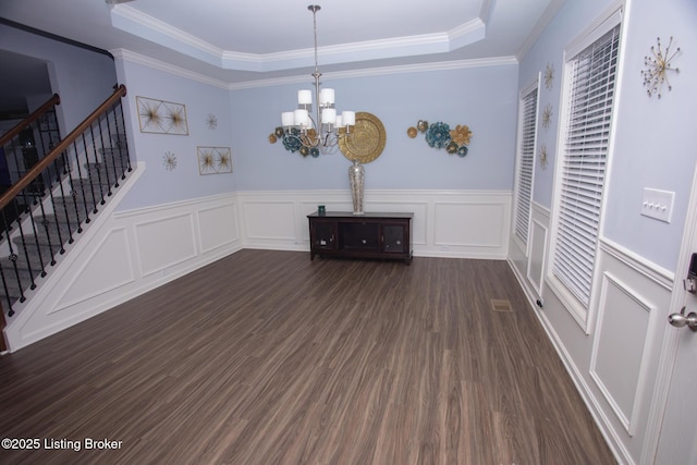 interior space with a notable chandelier, a tray ceiling, dark wood-type flooring, and ornamental molding