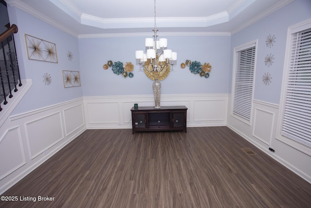 unfurnished dining area featuring crown molding, dark wood-type flooring, and a tray ceiling