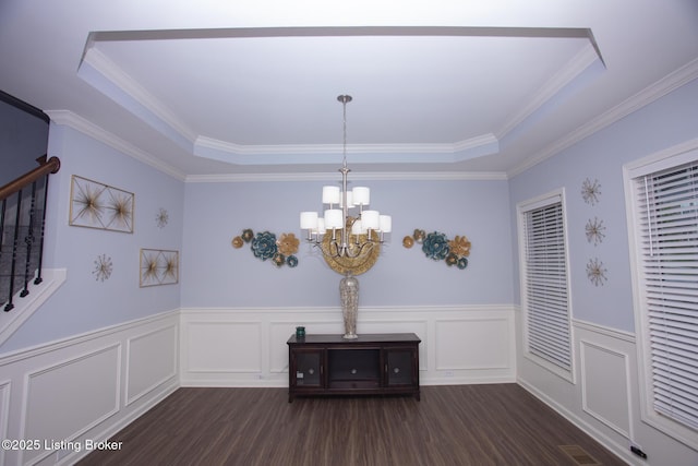 unfurnished dining area with an inviting chandelier, ornamental molding, and a raised ceiling