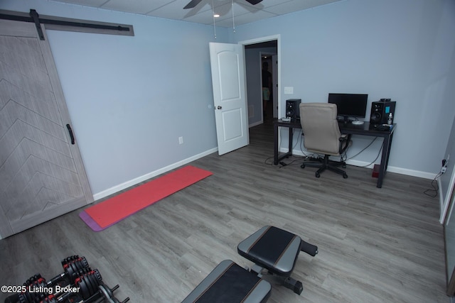 office space with wood-type flooring, a barn door, and ceiling fan