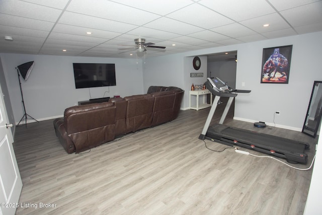 workout area with ceiling fan, a drop ceiling, and light wood-type flooring