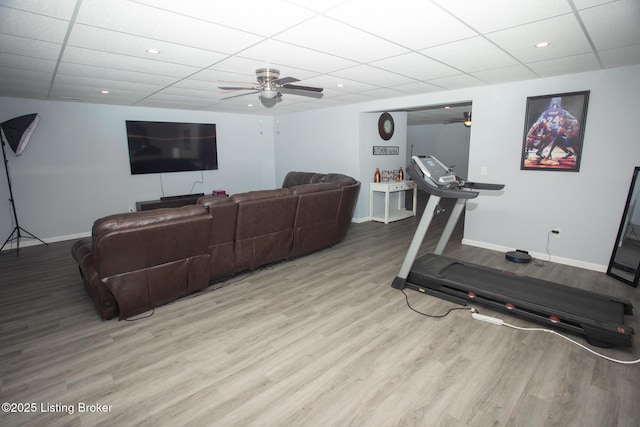 workout area with a paneled ceiling, ceiling fan, and light hardwood / wood-style flooring