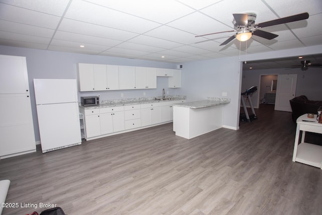 kitchen with a paneled ceiling, sink, white cabinets, white fridge, and light stone countertops