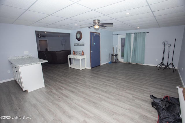 living room with wood-type flooring, a drop ceiling, and ceiling fan