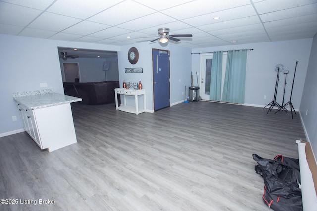 living room featuring hardwood / wood-style flooring, a paneled ceiling, and ceiling fan