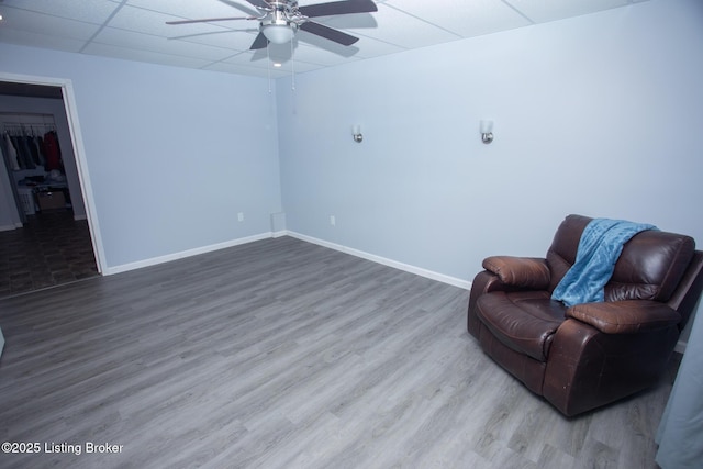 sitting room with ceiling fan, wood-type flooring, and a drop ceiling