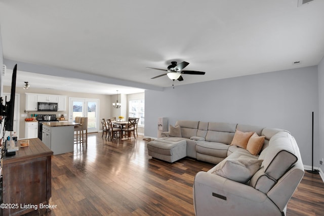 living room featuring dark wood-type flooring and ceiling fan with notable chandelier