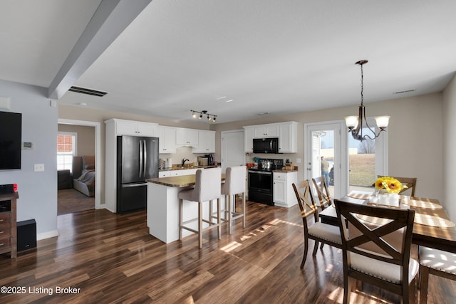 dining area with track lighting, dark hardwood / wood-style flooring, sink, and a notable chandelier