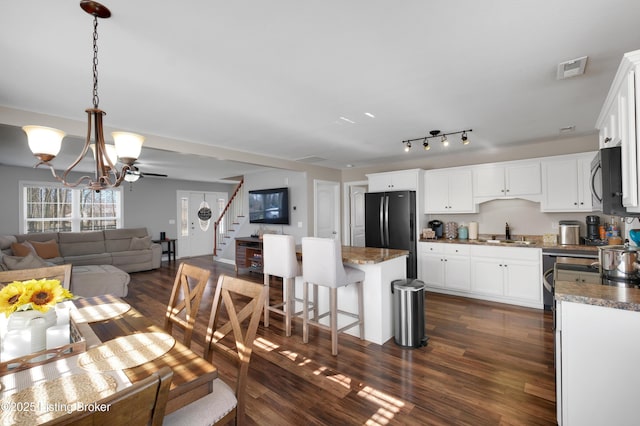 interior space featuring black fridge, white cabinetry, a center island, and pendant lighting