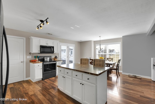 kitchen featuring white cabinetry, a kitchen island, dark hardwood / wood-style floors, black fridge, and stainless steel electric stove