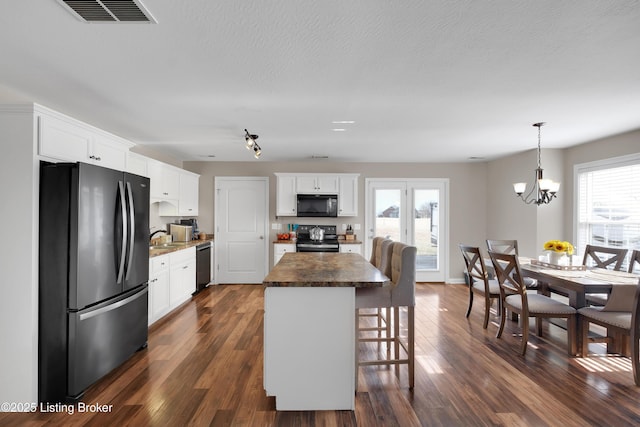 kitchen with dark wood-type flooring, black appliances, white cabinets, and a kitchen island