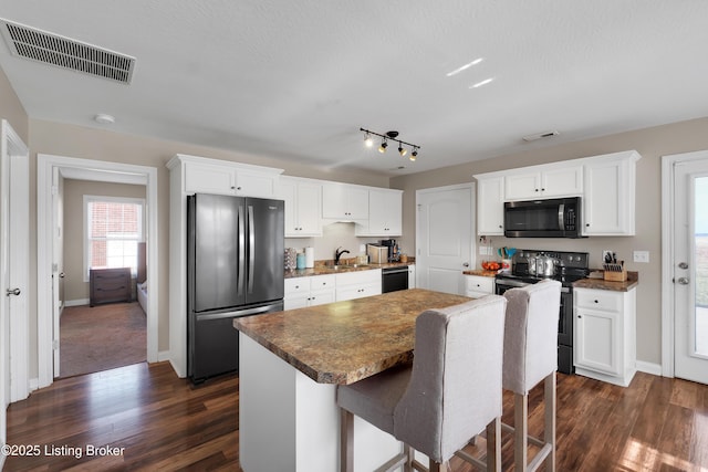 kitchen with sink, white cabinetry, a center island, stainless steel fridge, and range with electric cooktop