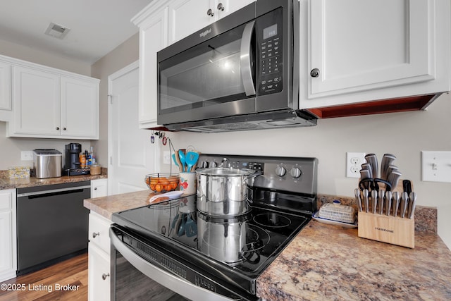 kitchen with white cabinets, wood-type flooring, and black appliances