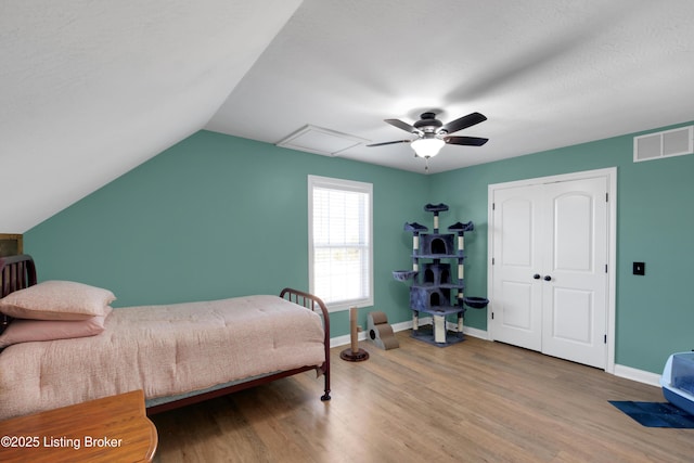 bedroom featuring lofted ceiling, a textured ceiling, light hardwood / wood-style flooring, and ceiling fan