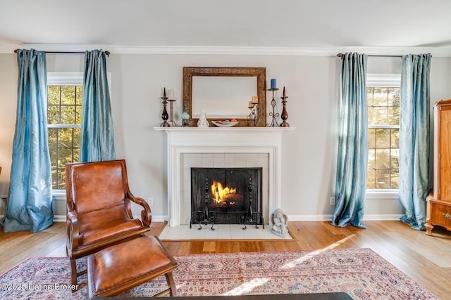 living area featuring a fireplace, crown molding, and light hardwood / wood-style flooring