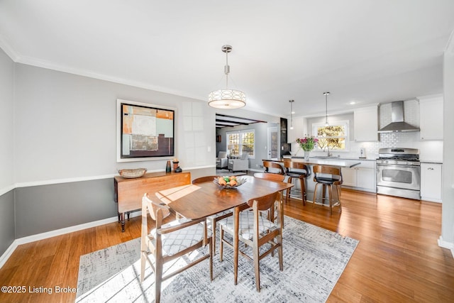 dining space with sink, ornamental molding, and light hardwood / wood-style floors