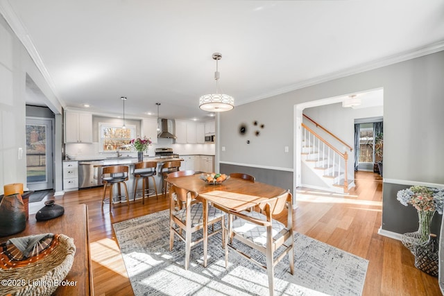 dining room with ornamental molding, sink, and light wood-type flooring