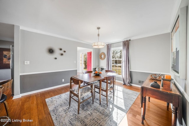 dining space with hardwood / wood-style flooring and crown molding