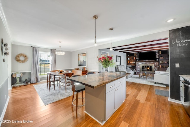 kitchen with a breakfast bar, white cabinetry, decorative light fixtures, a center island, and light wood-type flooring