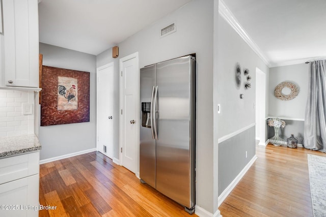 kitchen with crown molding, stainless steel fridge, tasteful backsplash, light hardwood / wood-style floors, and white cabinets