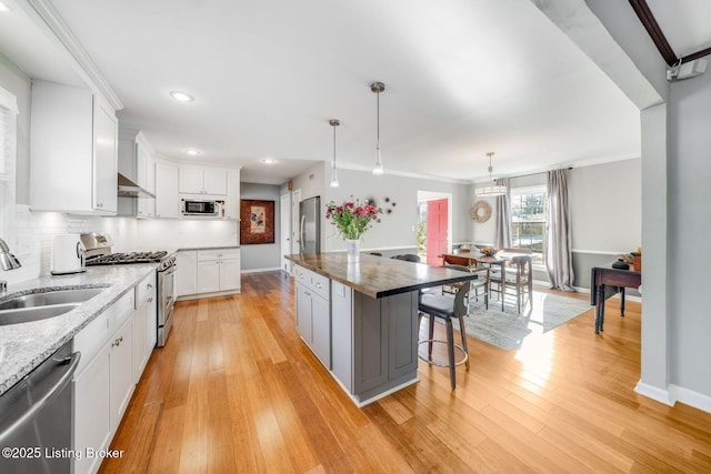 kitchen with sink, a breakfast bar area, white cabinets, a center island, and stainless steel appliances