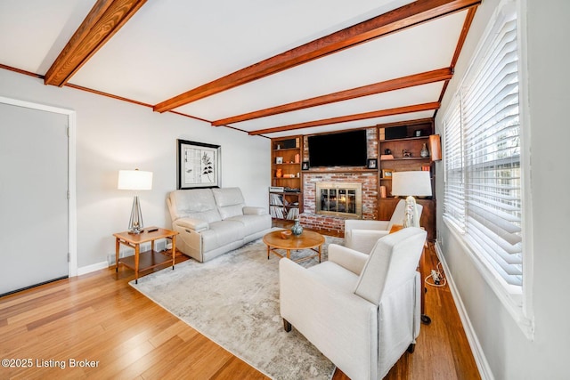 living room with a fireplace, beam ceiling, and light wood-type flooring