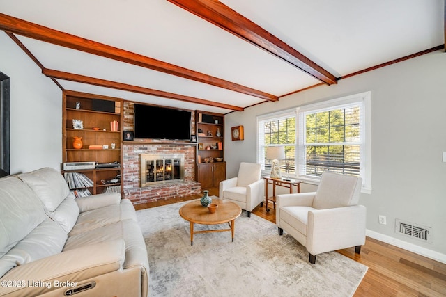 living room with beam ceiling, a fireplace, and light hardwood / wood-style floors