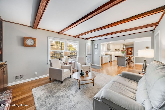 living room with beamed ceiling and light wood-type flooring