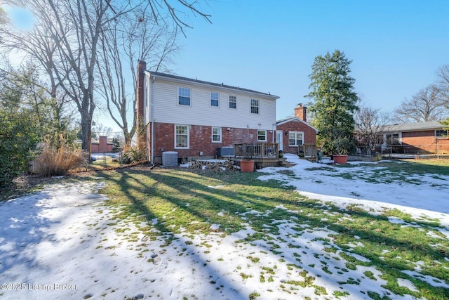 snow covered back of property featuring a wooden deck, a yard, and cooling unit