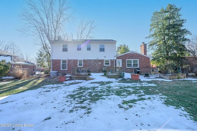 snow covered property with cooling unit and a lawn