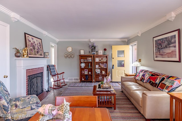 living room featuring a brick fireplace, crown molding, and wood-type flooring