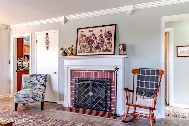 sitting room with ornamental molding, wood-type flooring, and a fireplace