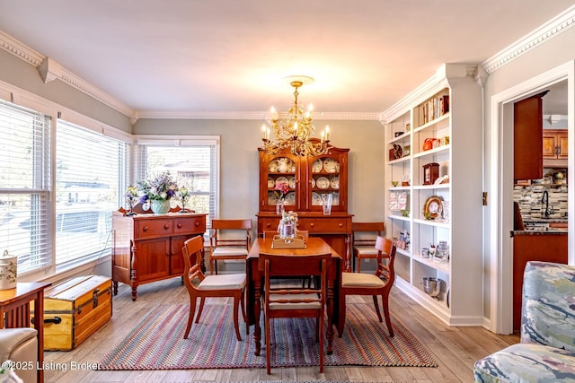 dining space featuring ornamental molding, light hardwood / wood-style floors, and a notable chandelier