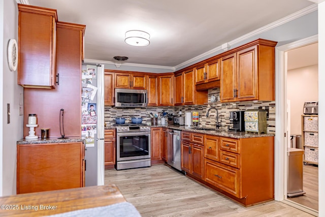 kitchen with stone counters, sink, light hardwood / wood-style floors, stainless steel appliances, and crown molding