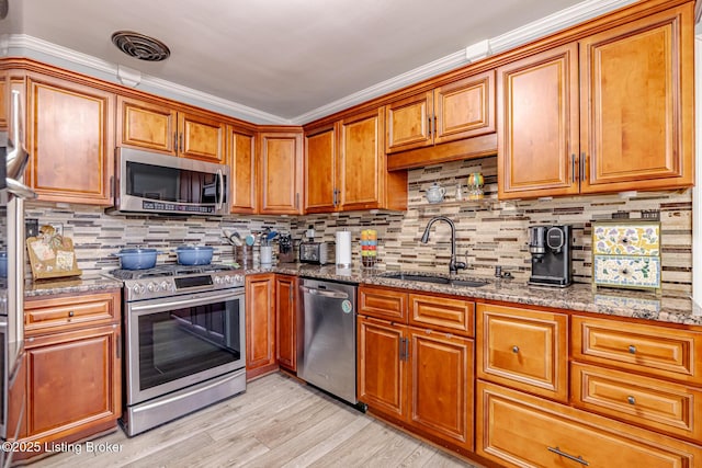 kitchen with sink, decorative backsplash, light stone countertops, and appliances with stainless steel finishes