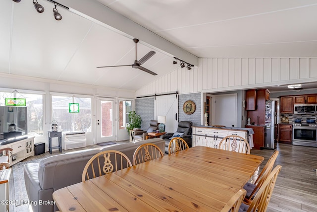 dining space with brick wall, hardwood / wood-style floors, lofted ceiling with beams, ceiling fan, and a barn door