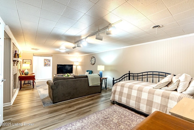 bedroom with hardwood / wood-style flooring, crown molding, and track lighting