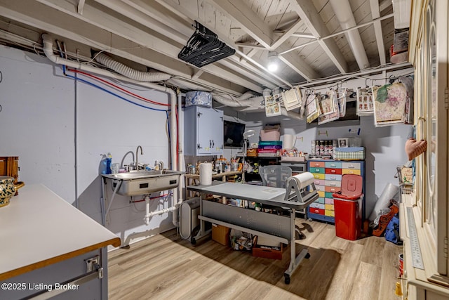 basement with sink and light hardwood / wood-style floors