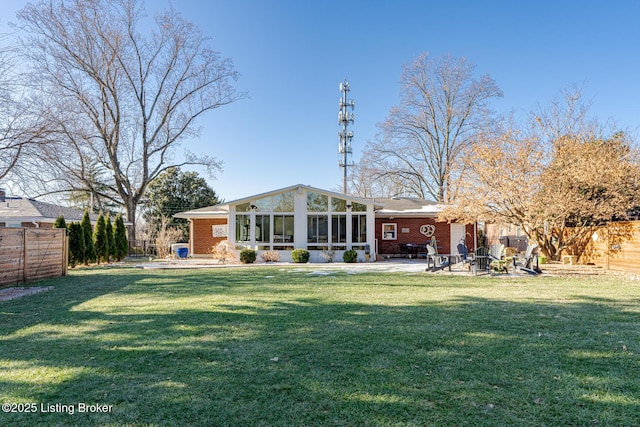 rear view of property with a sunroom, a patio area, and a lawn