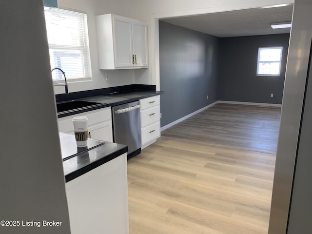 kitchen with sink, white cabinetry, dishwasher, a healthy amount of sunlight, and light hardwood / wood-style floors