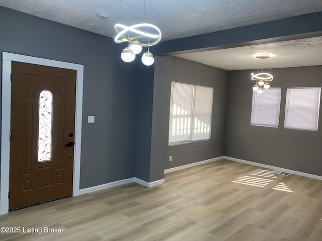 foyer with hardwood / wood-style flooring, plenty of natural light, a notable chandelier, and a textured ceiling